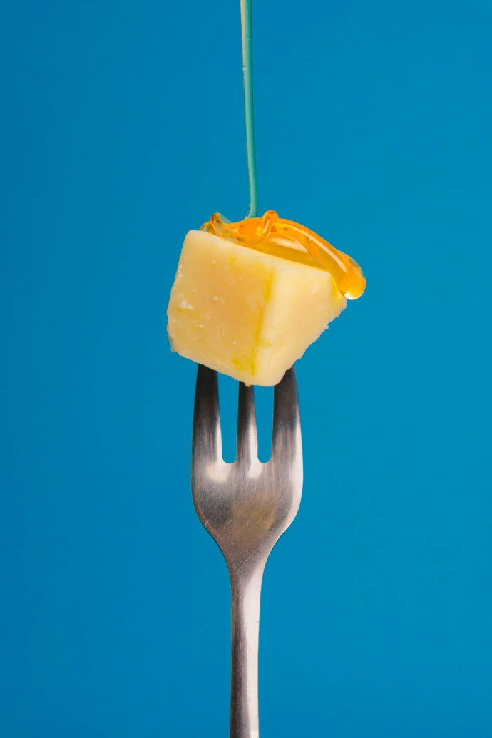 a fork with a piece of cheese on top of it